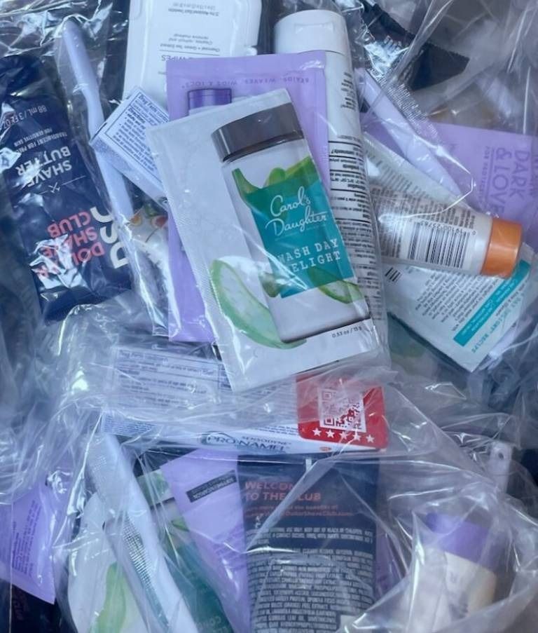 Pile of travel-sized toiletries in clear plastic, including toothpaste, lotions, and razors.