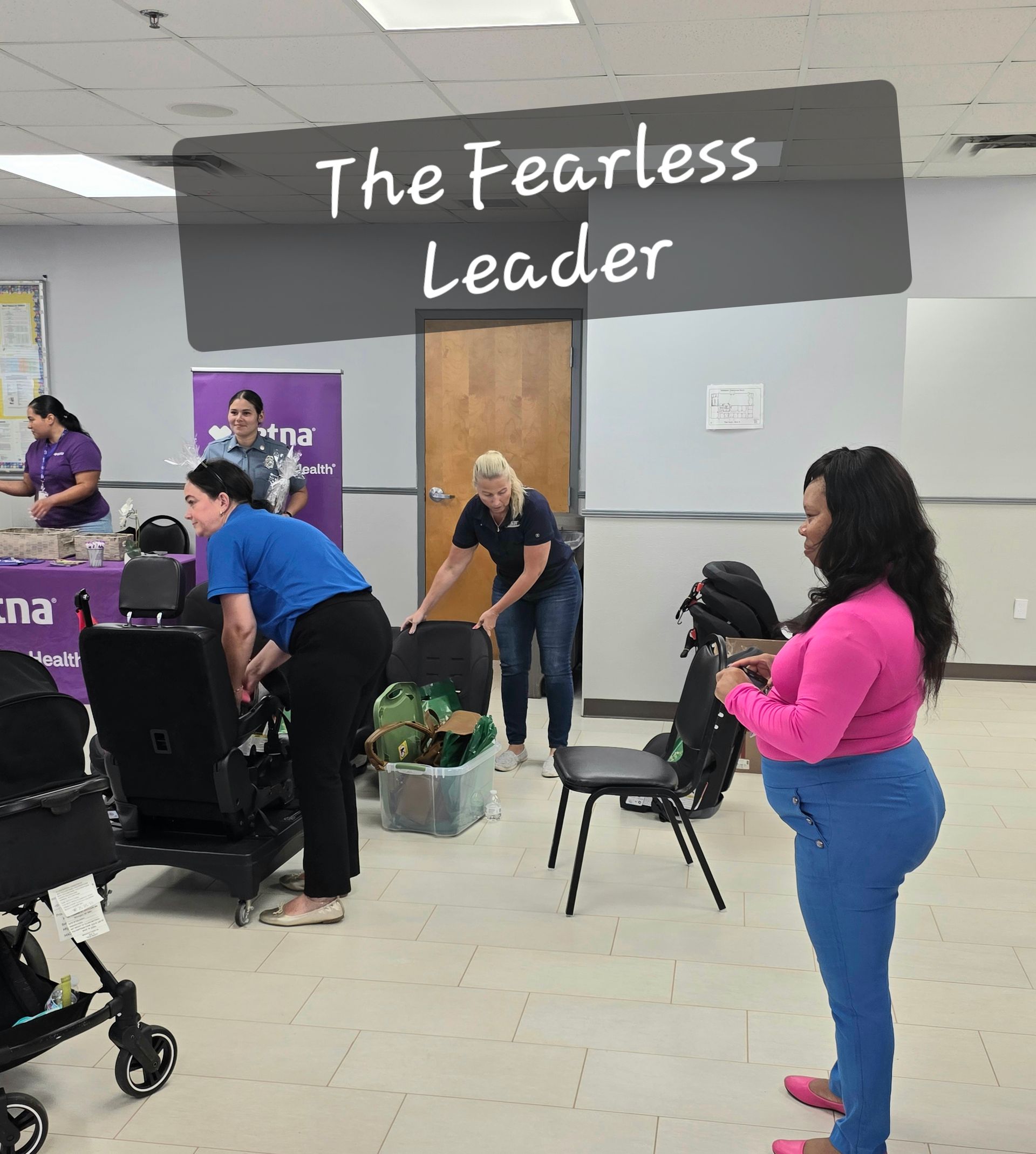 People arranging items in a room under a sign reading “The Fearless Leader”