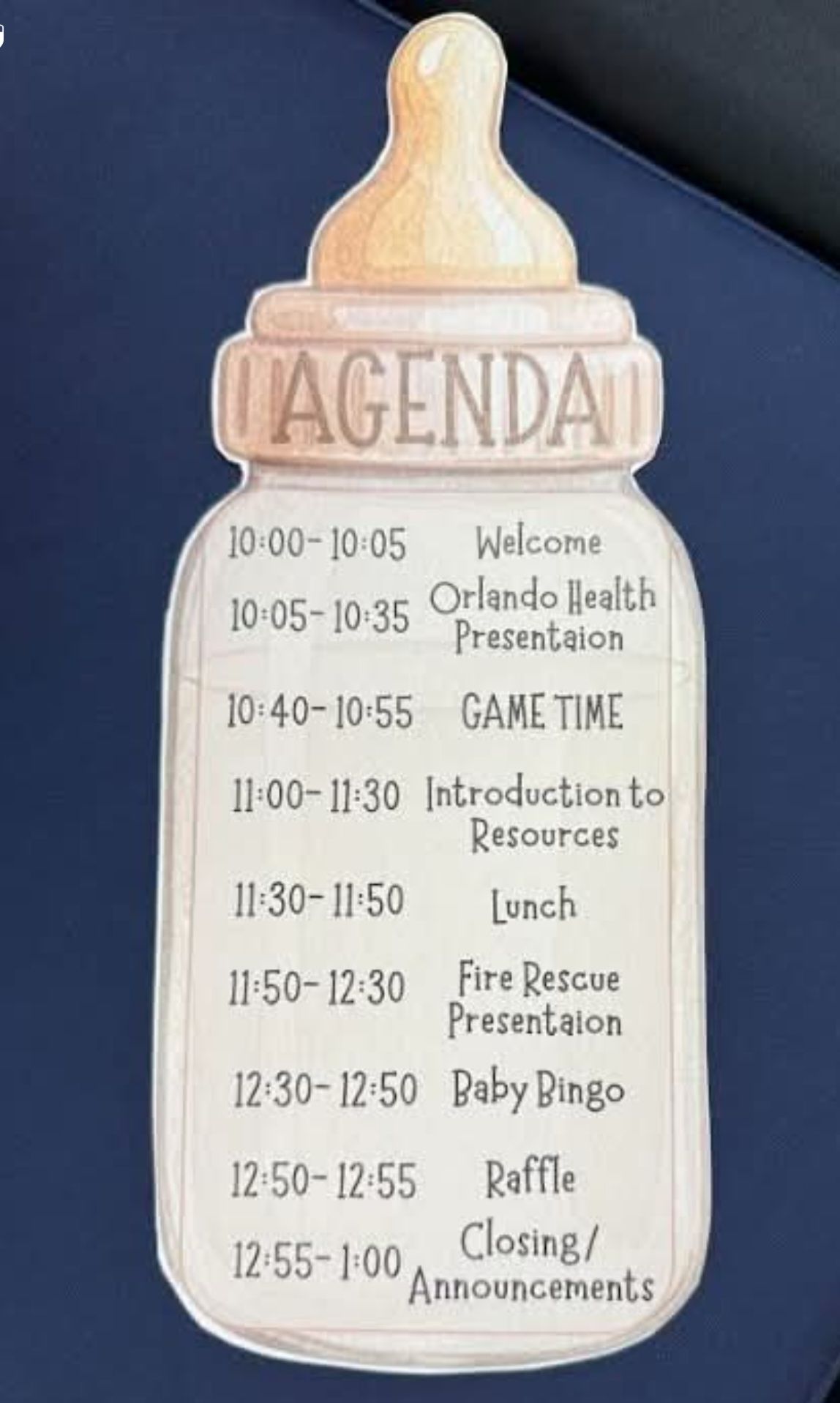 Agenda sign with cream and gold balloon-like top listing event schedule on blue background
