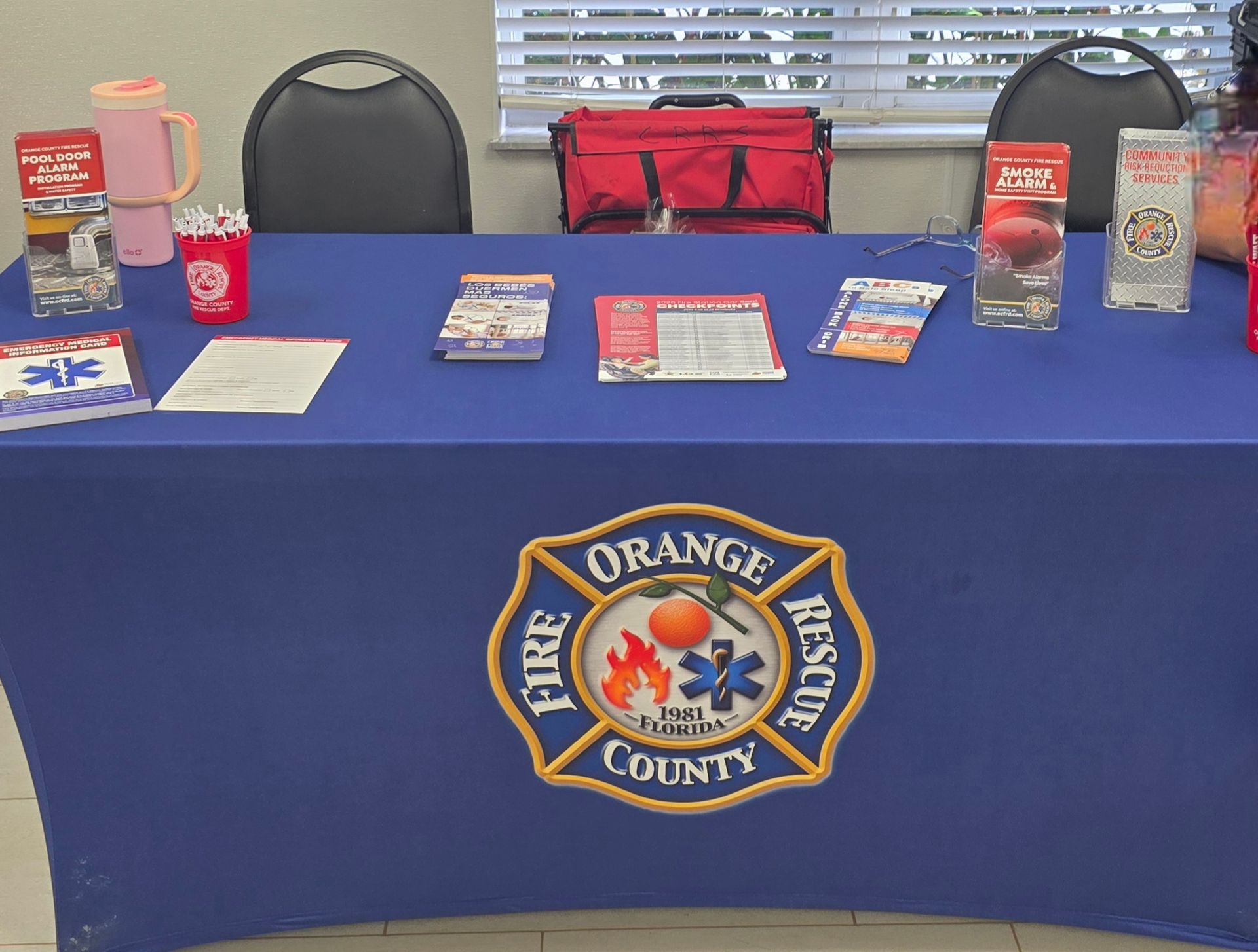 Orange County Fire Rescue display table with brochures, water bottles, and a red bag on a blue tablecloth