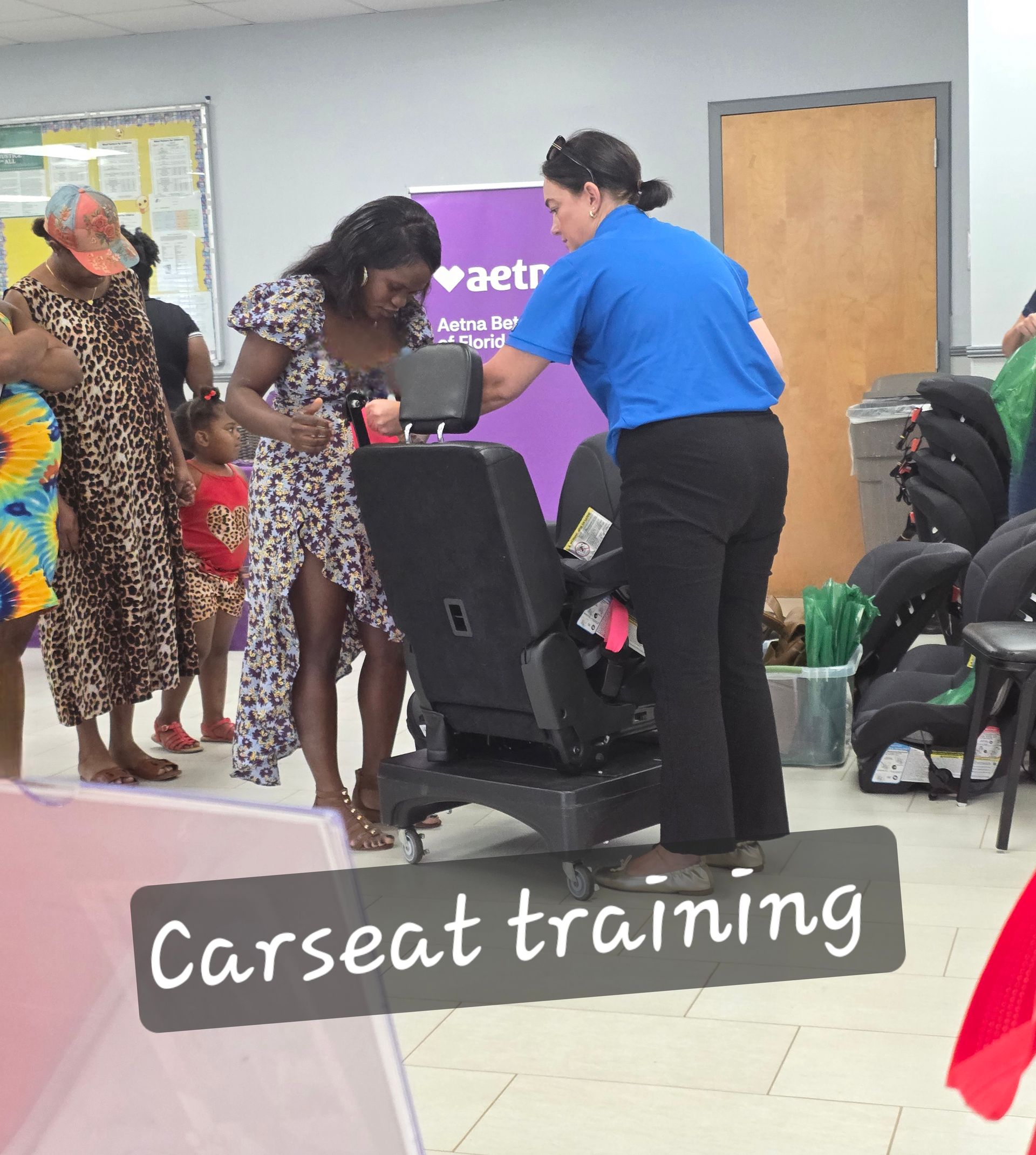 People receiving car seat training from an instructor in a community room