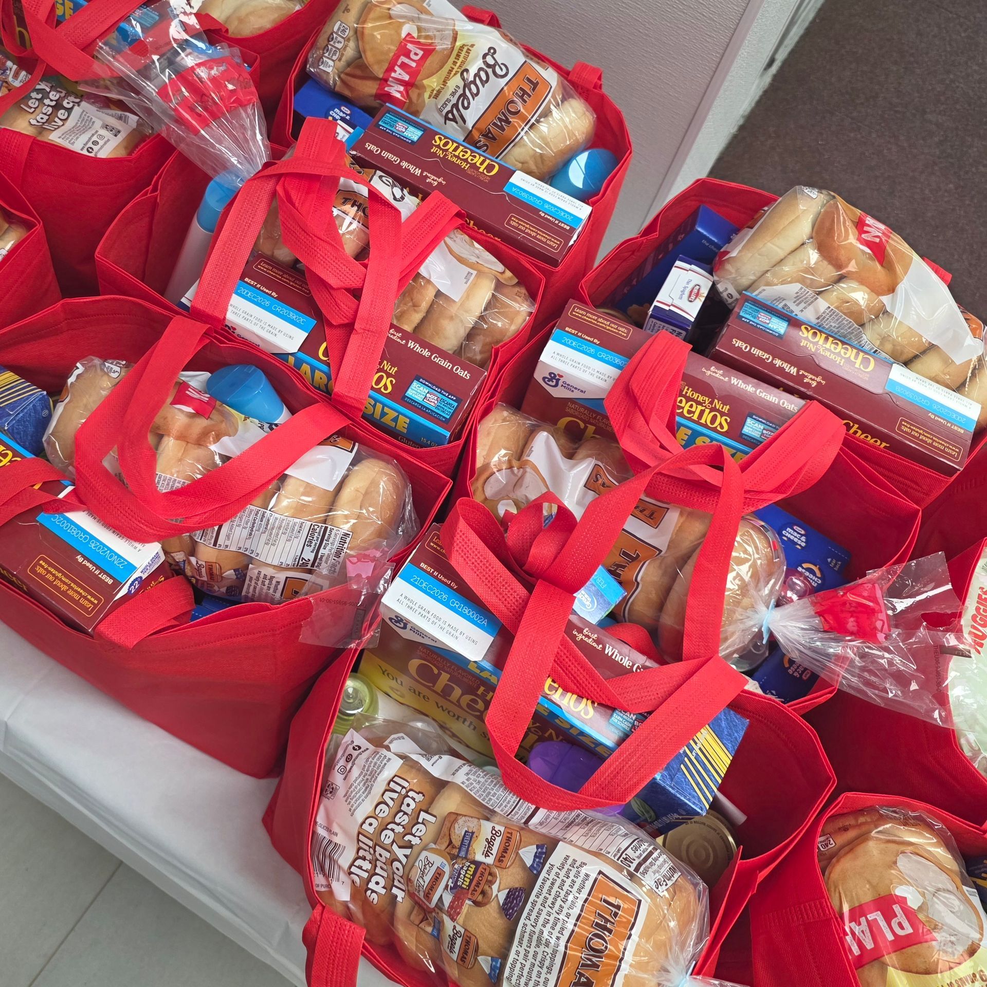 Red gift bags filled with wrapped snacks and small food items on a table