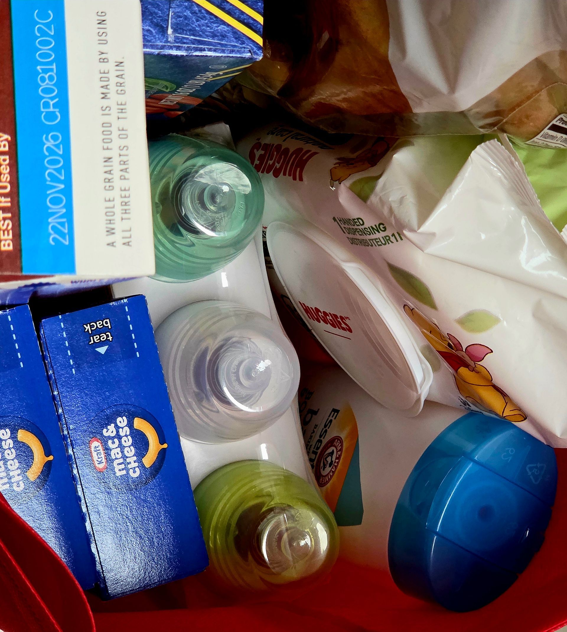 Assorted toiletries and household items in a red bin, including soap boxes, bottles, and tubes.