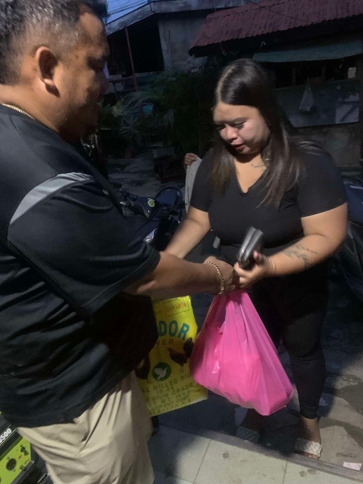 Man handing items to a woman holding a pink bag outside a building | Redhawk Auto Service - Temecula