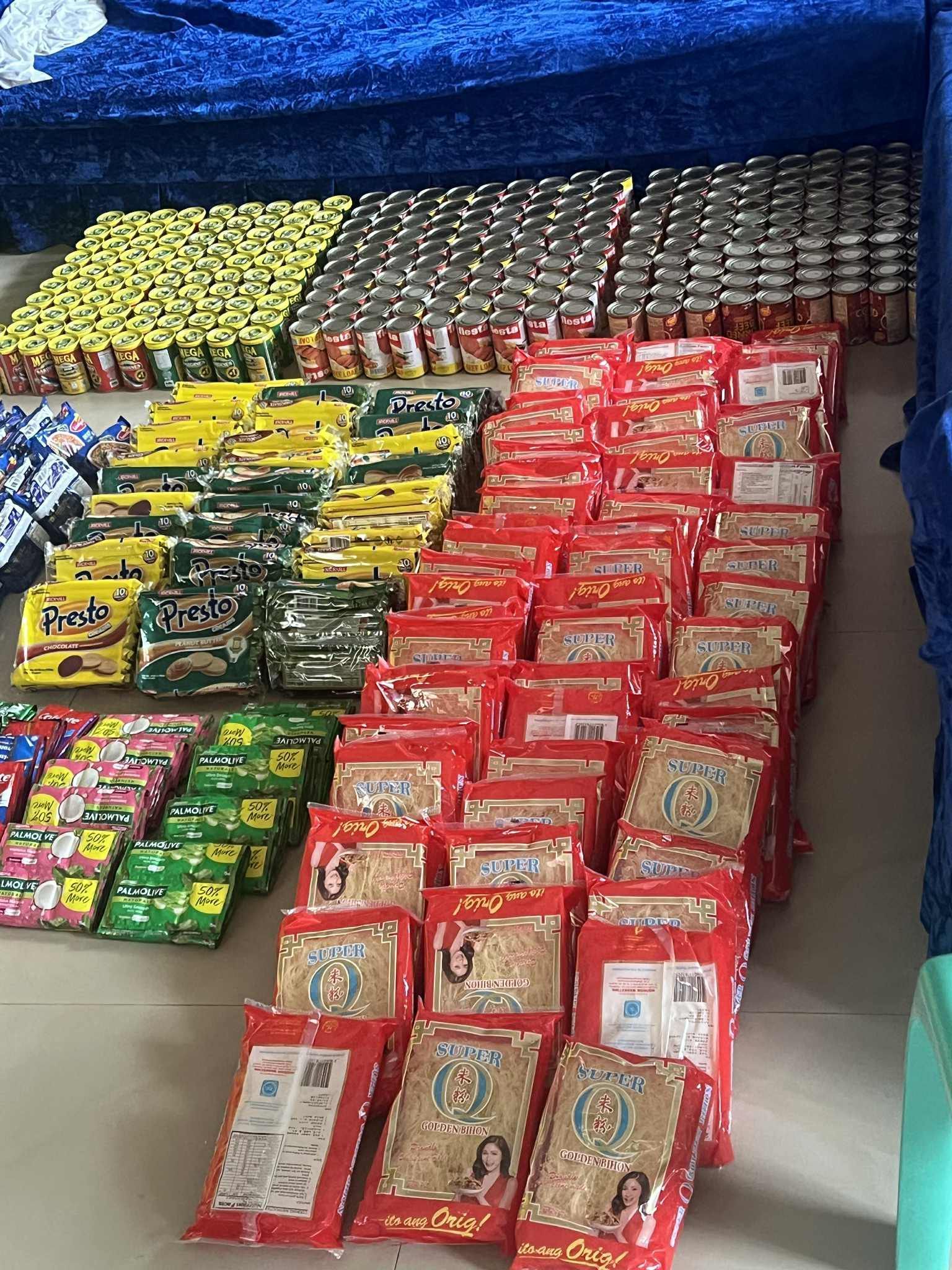 Neatly stacked assorted snack packets in rows, mostly red, yellow, green, and silver, on a tiled floor. | Redhawk Auto Service - Temecula