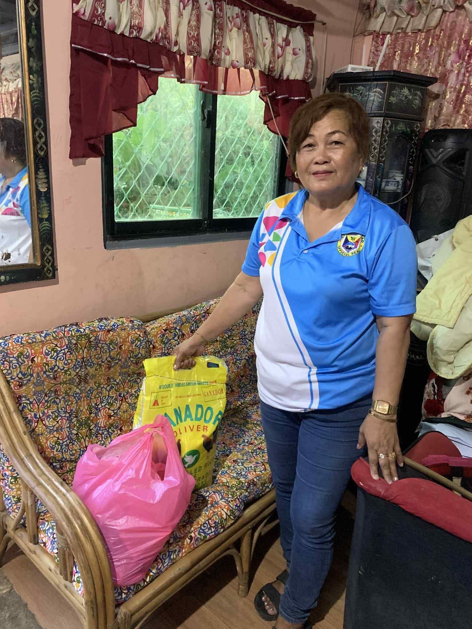 Woman standing beside a floral sofa in a living room, holding shopping bags near a window. | Redhawk Auto Service - Temecula