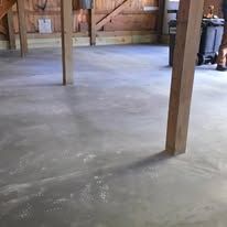 Empty unfinished room with a concrete floor, wooden support posts, and exposed wall framing.
