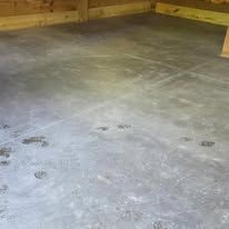 Concrete floor in a wooden room, with several dark paw prints scattered across it.