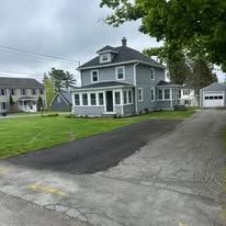 Gray two-story house with white trim, front porch, and driveway on a suburban street