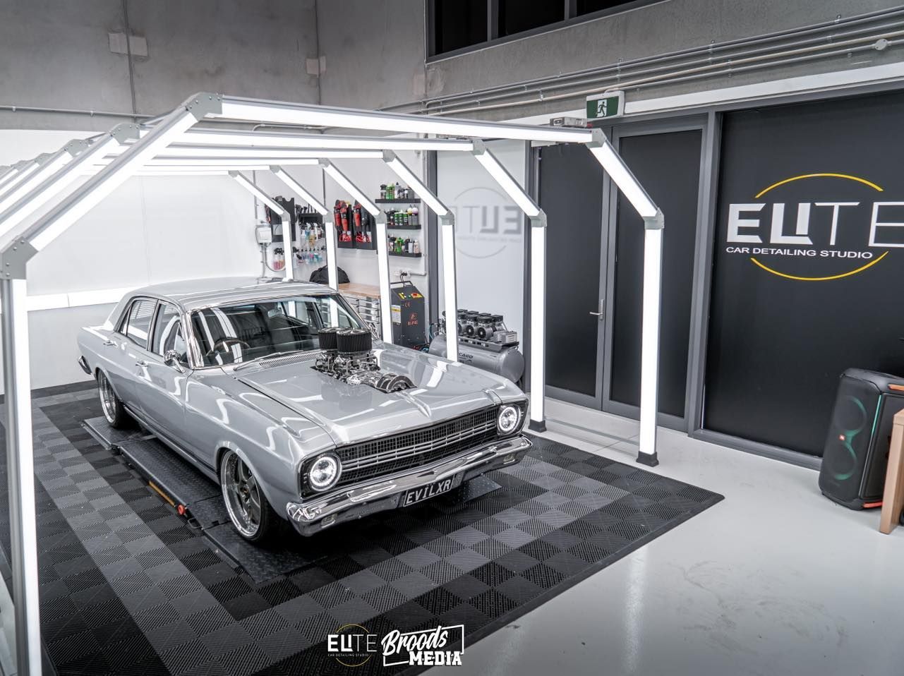 A silver car is parked under a canopy in a garage.