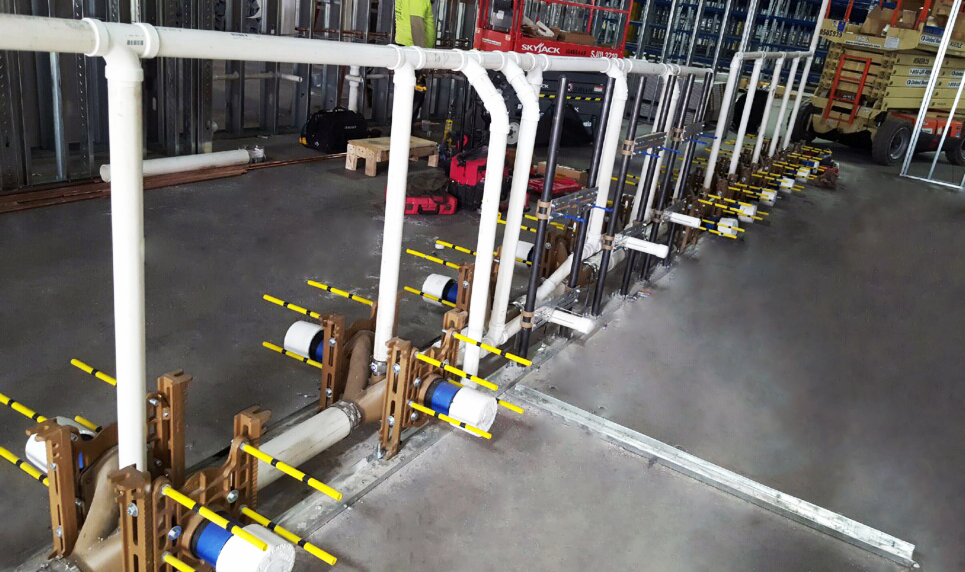 A row of pipes are lined up in a warehouse.