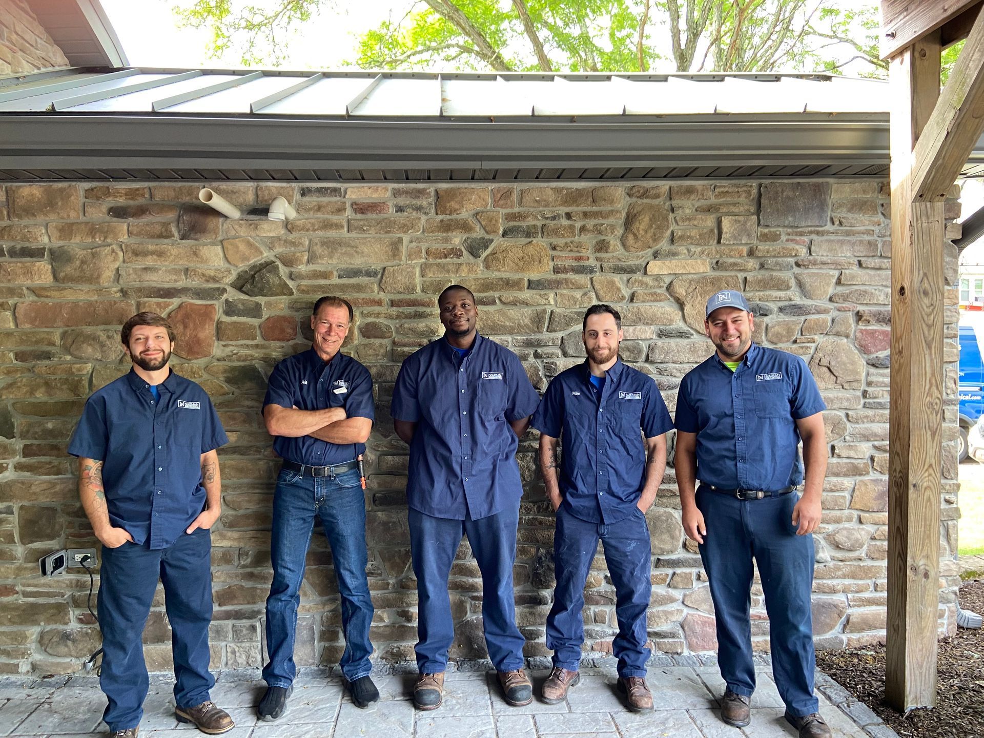 A group from Nauman Inc. standing next to each other in front of a stone wall.
