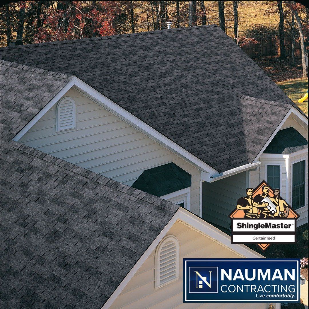 A house with shingles on the roof and a sign that says nauman contracting