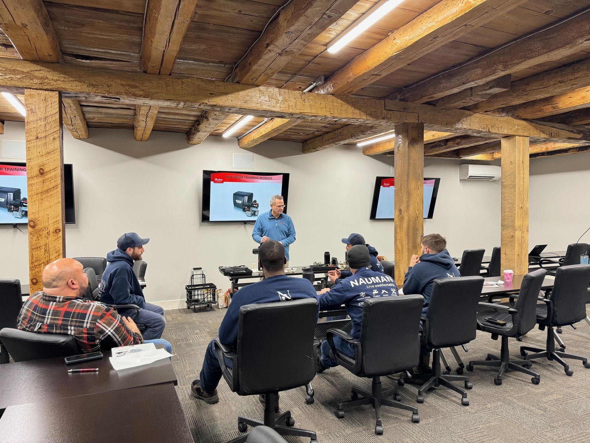 A man is giving a presentation to a group from Nauman Inc. in a conference room.
