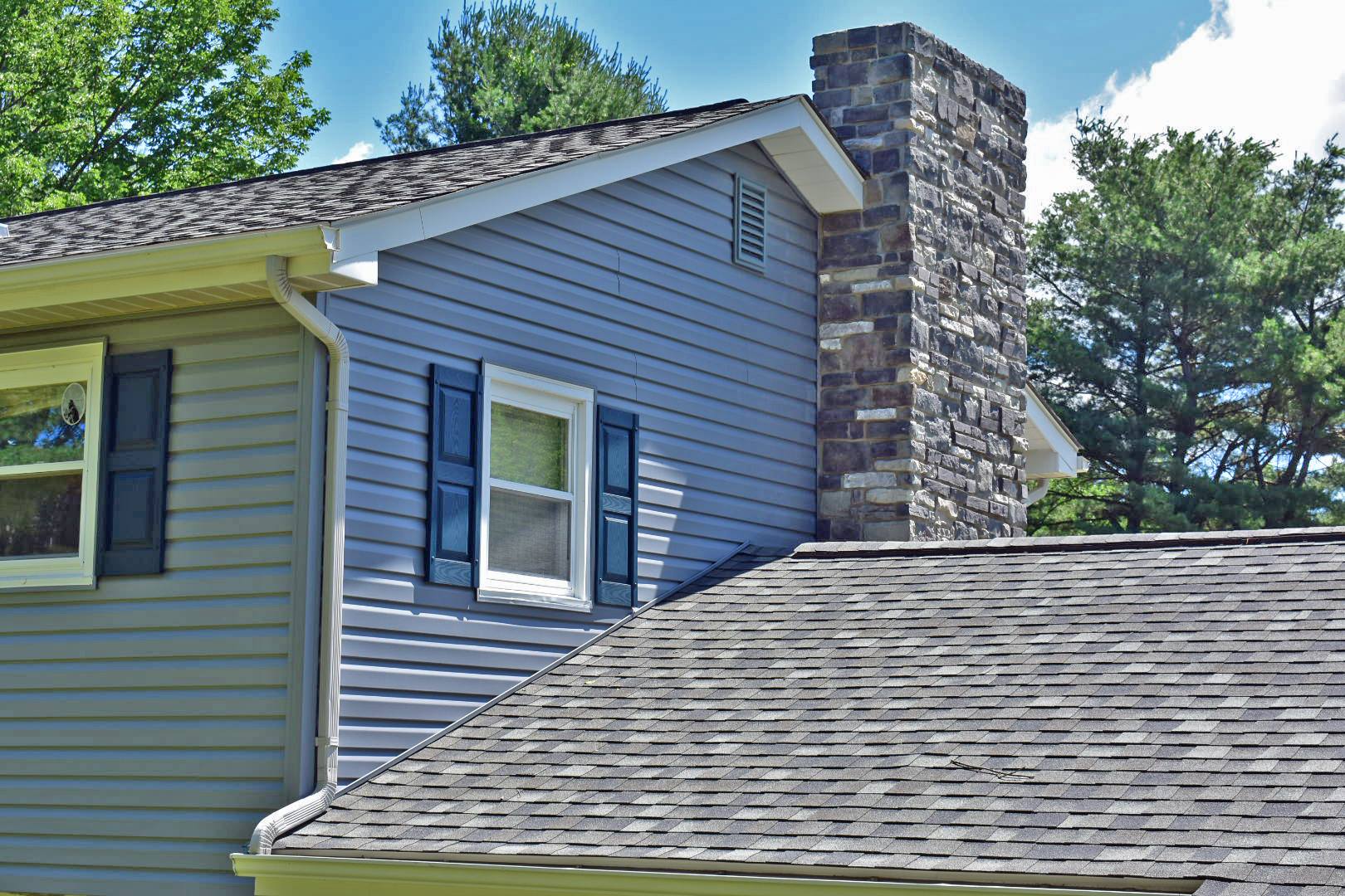 A house with a stone chimney on the side of it.