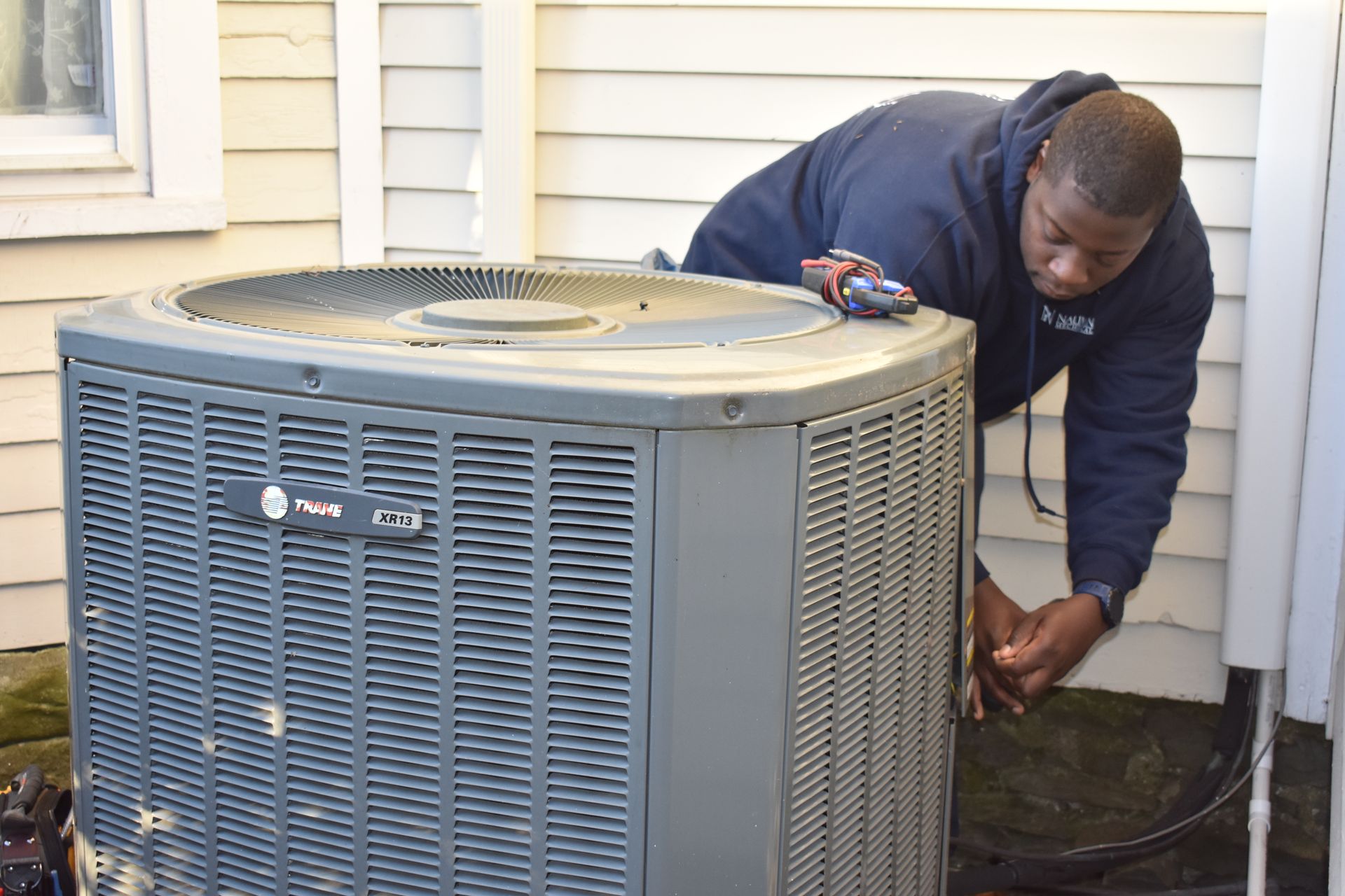 Nauman HVAC specialist is working on an air conditioner outside of a house.
