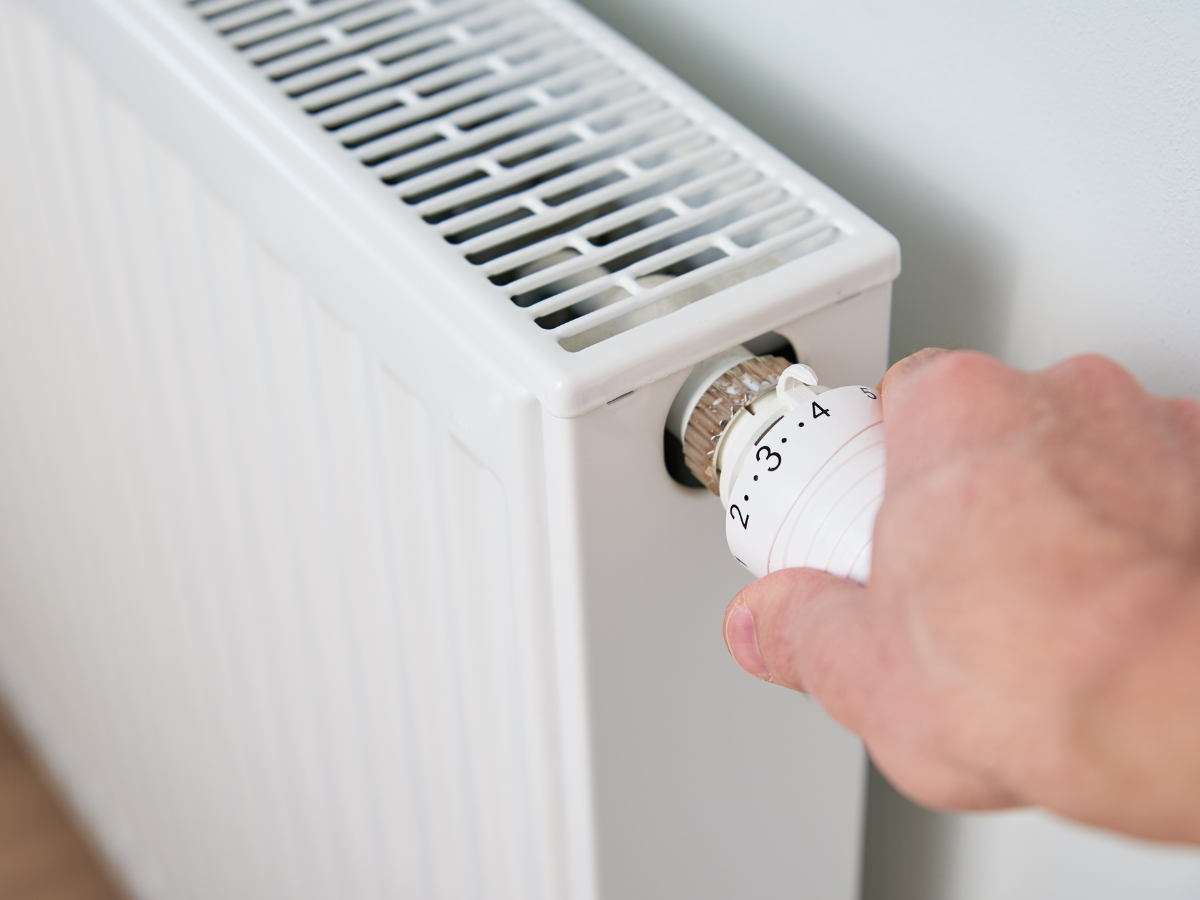 A person is adjusting a thermostat on a radiator. A person is adjusting a thermostat on a radiator.