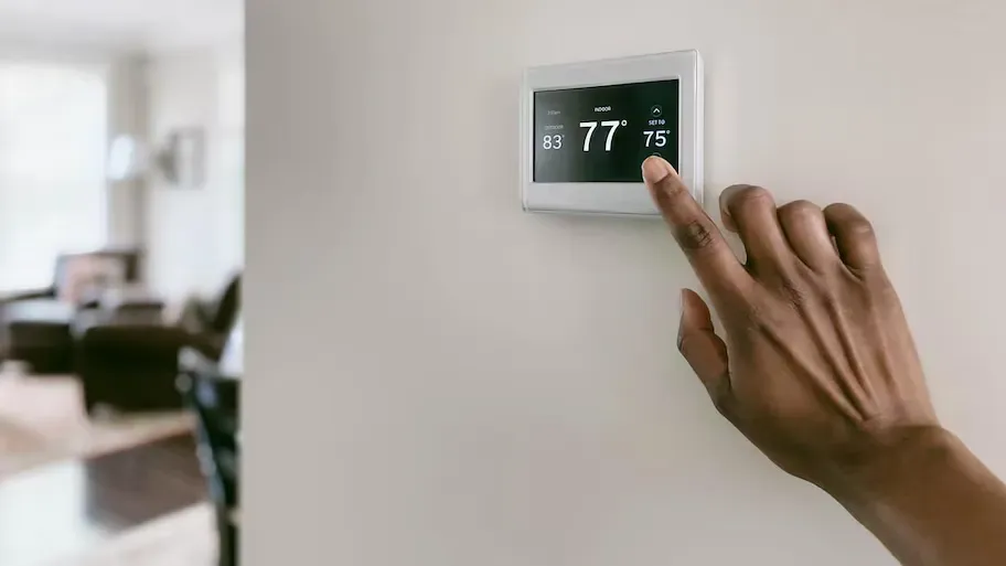 A person is adjusting a thermostat on a wall in a living room. A person is adjusting a thermostat on a wall in a living room.