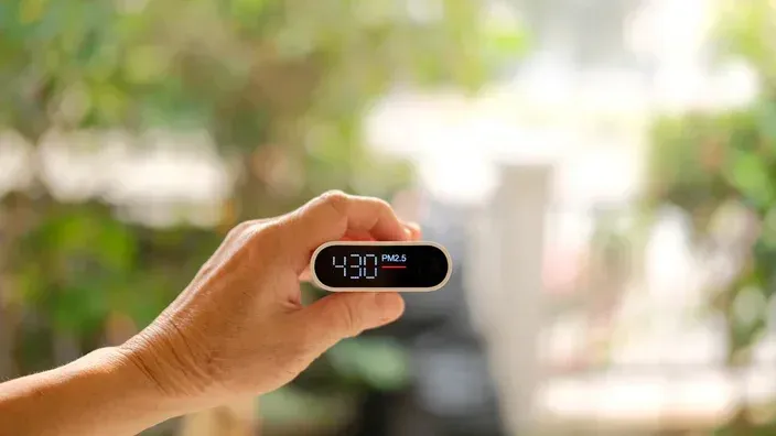 A person is holding a small electronic device in their hand. A person is holding a small electronic device in their hand.