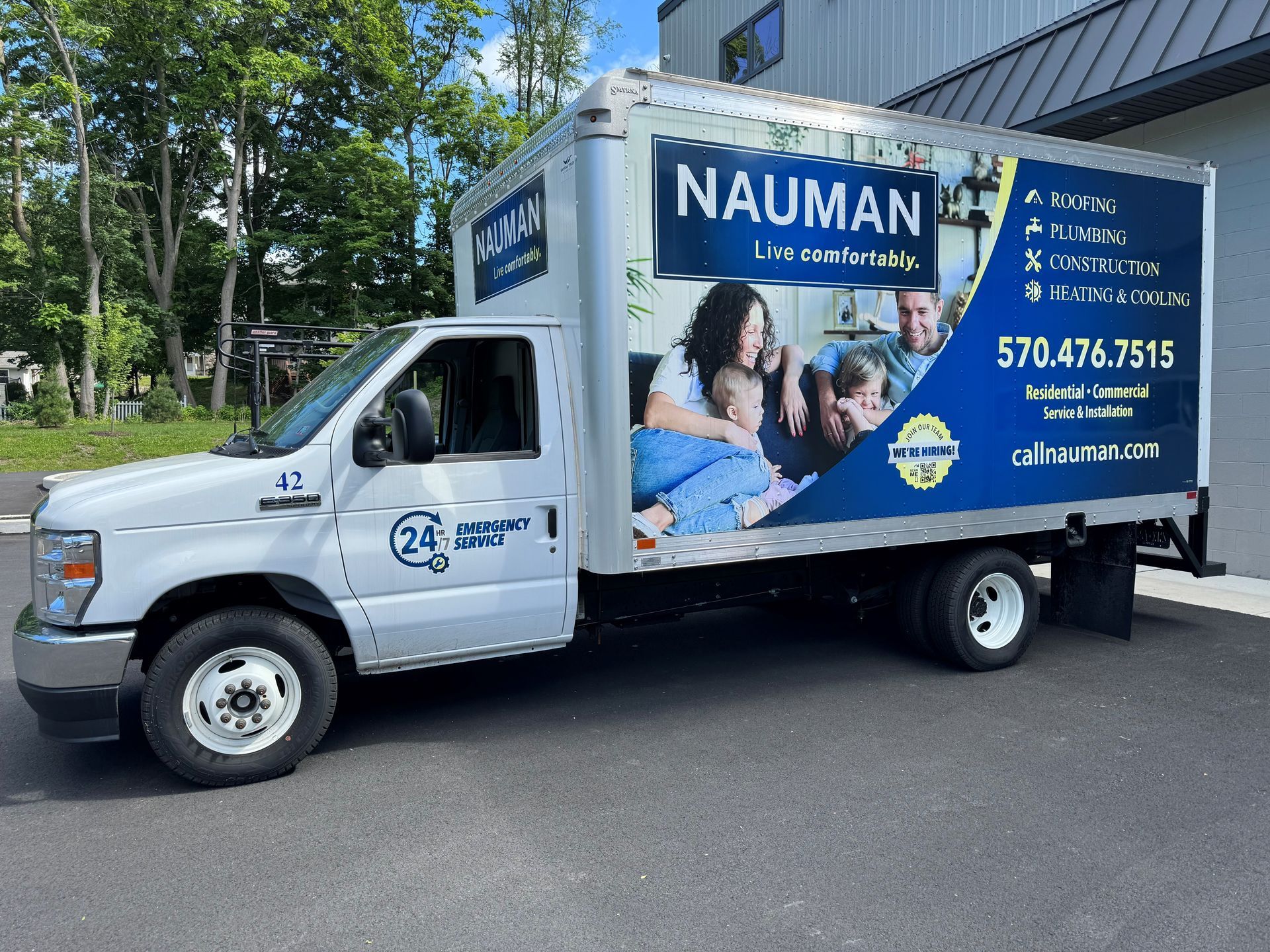 A worker from Nauman Inc. is working on an air conditioner outside of a house.