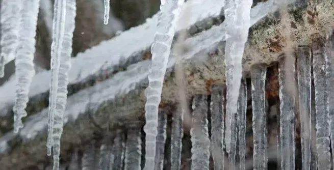 Frozen pipes against a house with icicles hanging down from it. Frozen pipes against a house with icicles hanging down from it.