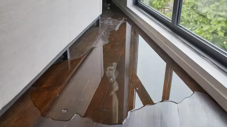 A flooded floor in a room next to a window. A flooded floor in a room next to a window.