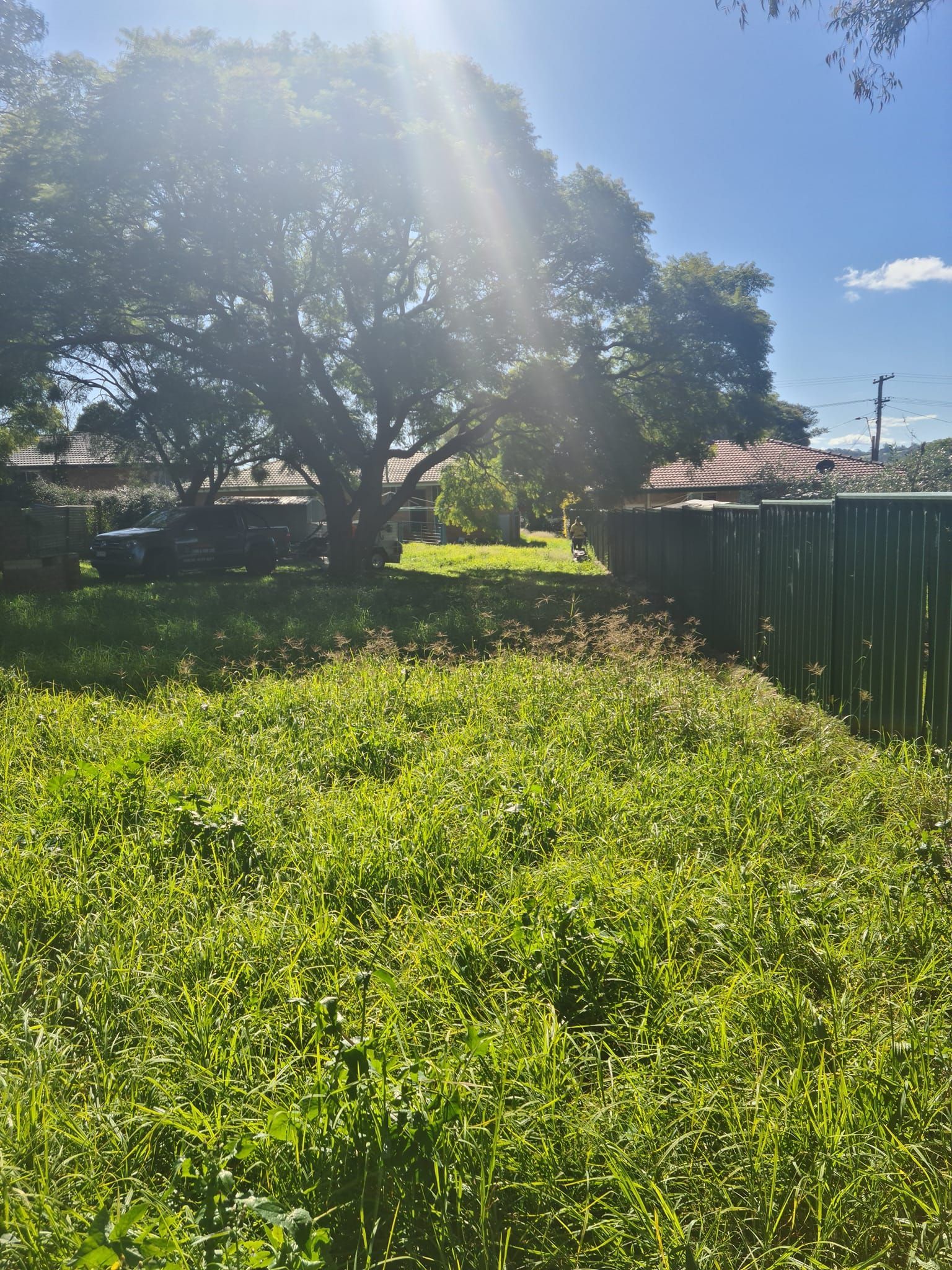 Person In An Orange Jacket Holds Up A Camera Outdoors In A Hilly Landscape — Toowoomba Lawn and Yard care In Glenvale, QLD