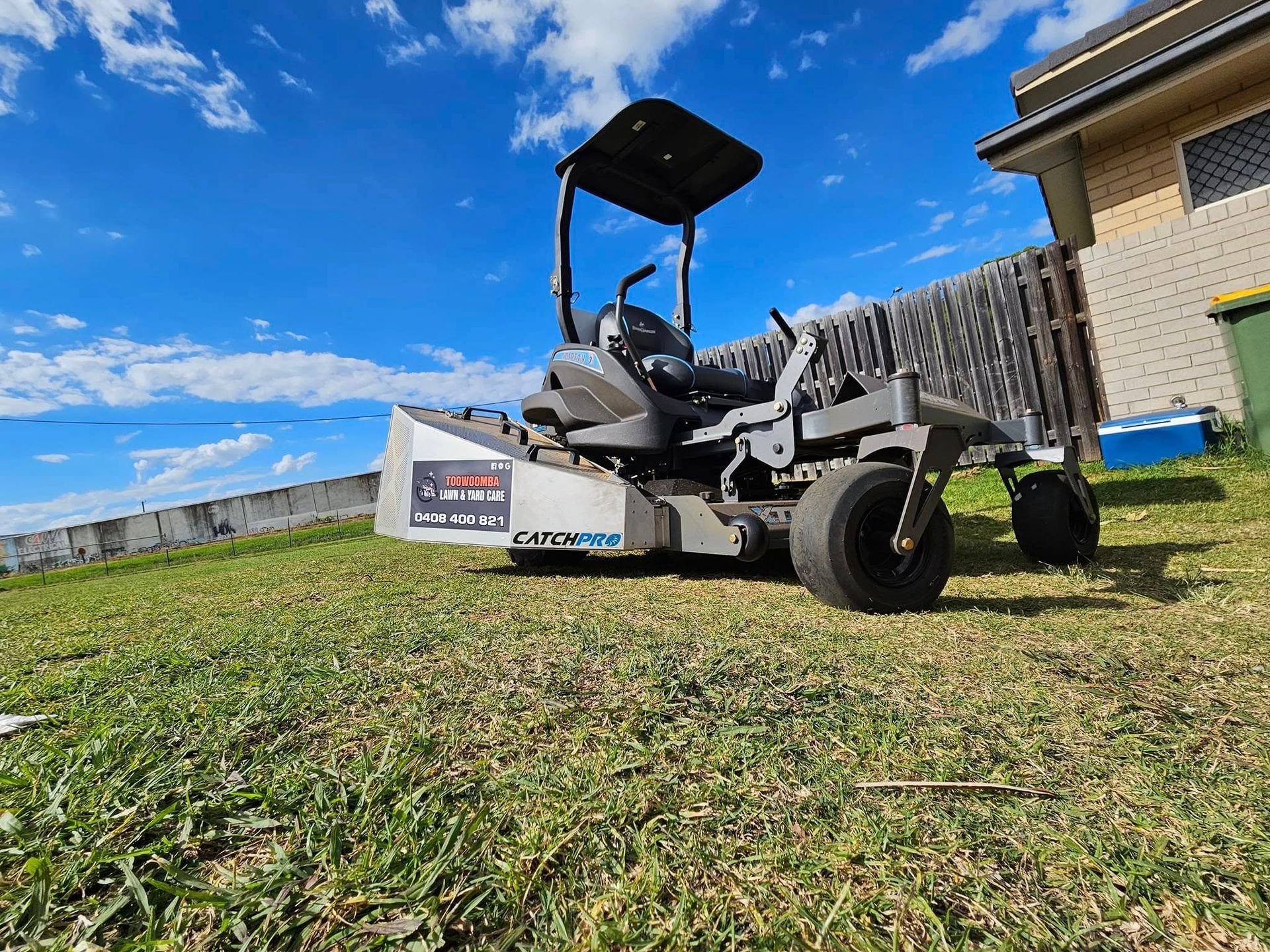 Grey Zero-turn Mower on a Grassy Lawn Beside a House — Toowoomba Lawn and Yard care In Glenvale, QLD