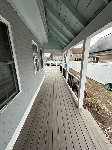 A long wooden walkway leading to a house with a white fence.