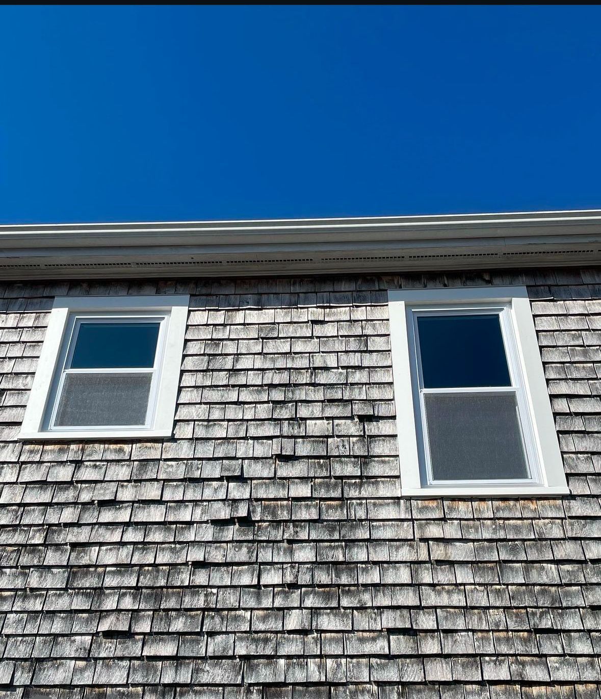 A brick building with two windows and a blue sky in the background