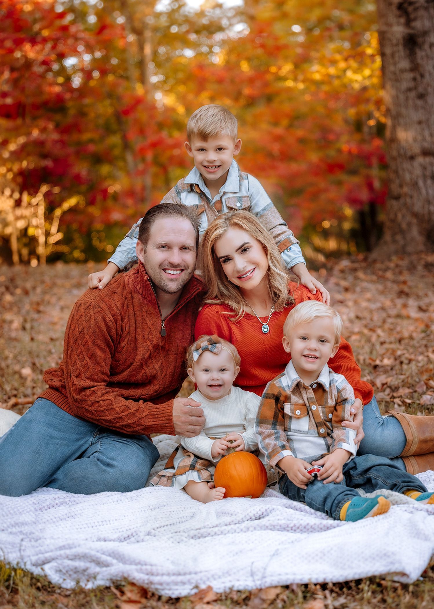 Family enjoying a fall portrait session surrounded by colorful autumn trees in Raleigh, NC