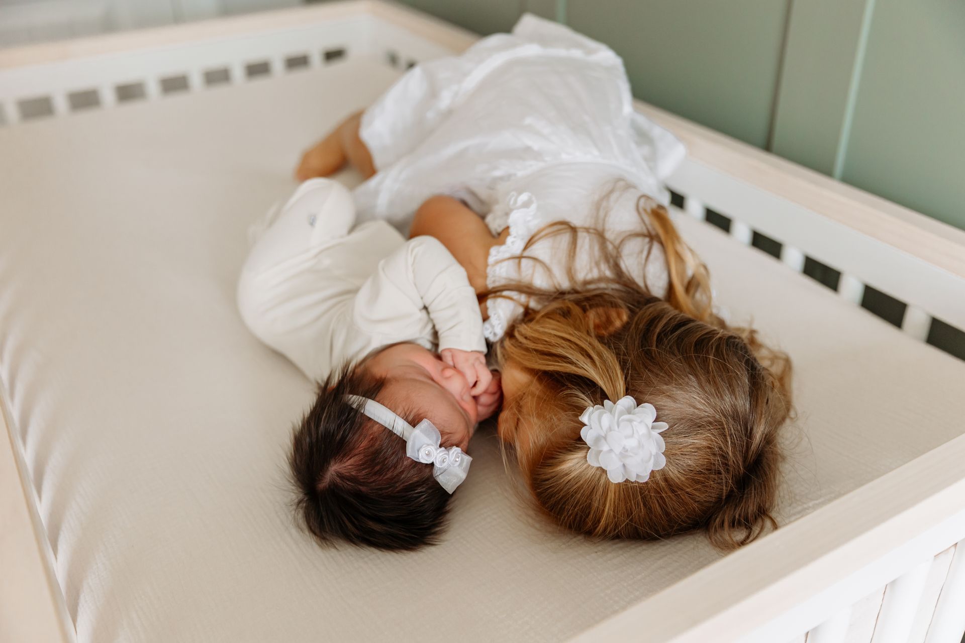 Peaceful newborn twins sleeping on soft neutral blankets in a bright studio