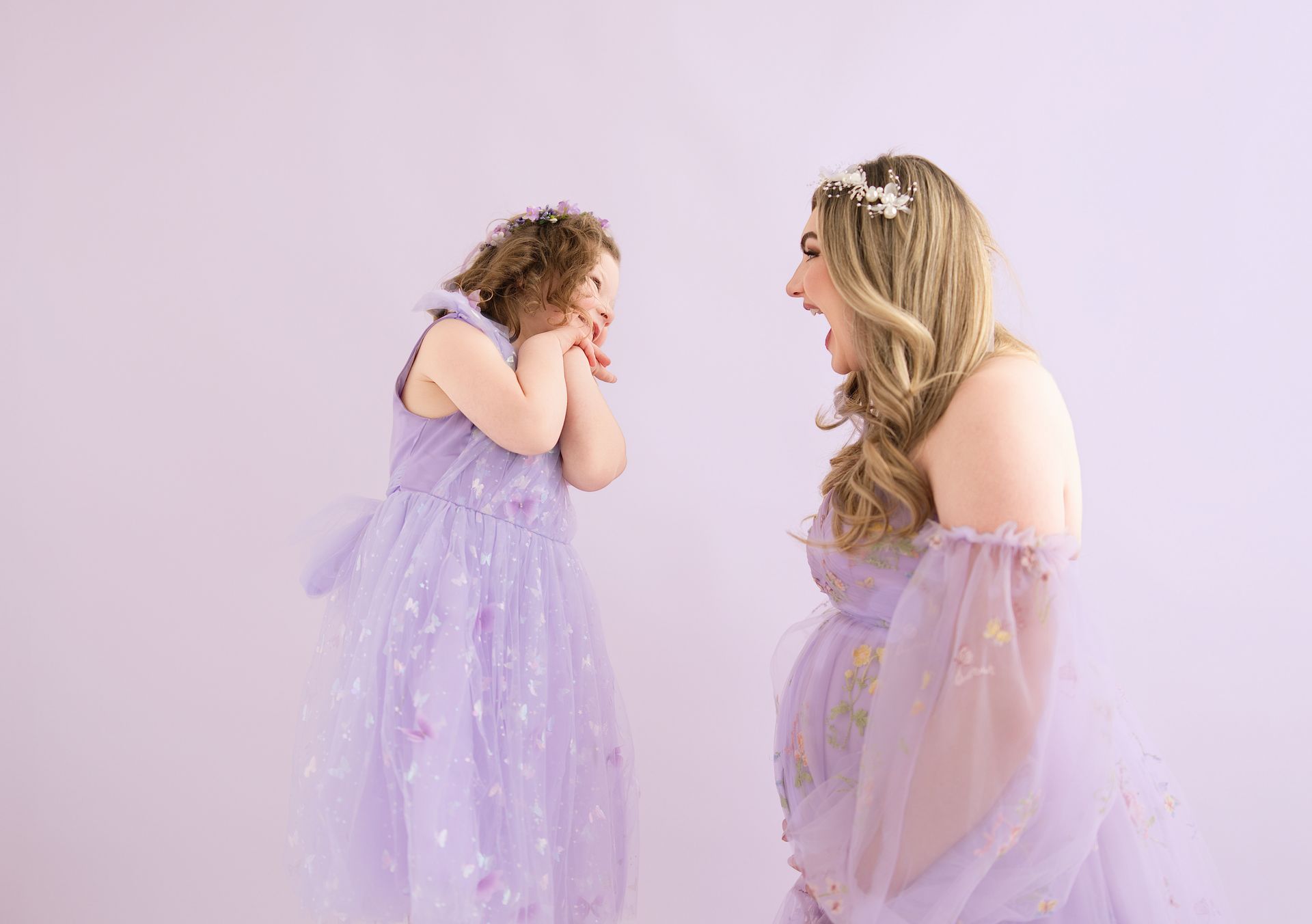 Mother and daughter laughing together during a fun purple-themed maternity and milestone session