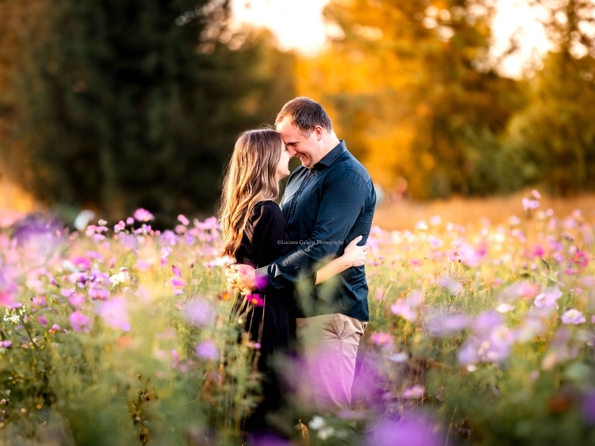 Happy mom, dad enjoying a golden hour photo session in a flower field in Raleigh