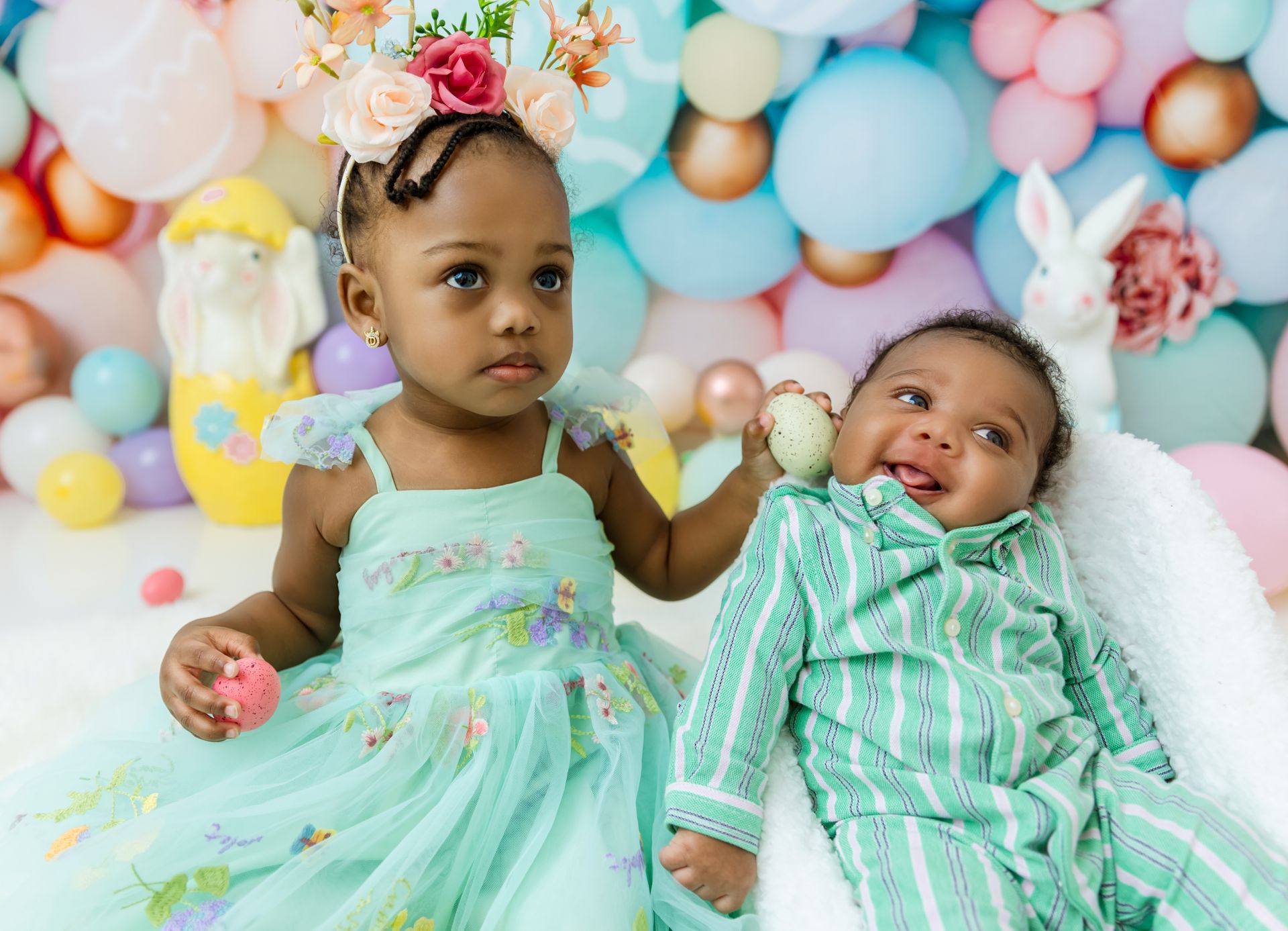 siblings during Easter mini session with pastel balloon backdrop in Cary NC studio