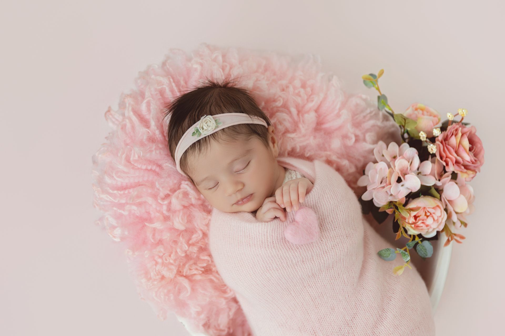 Sleeping newborn baby girl
in a pink swaddle during Cary studio session