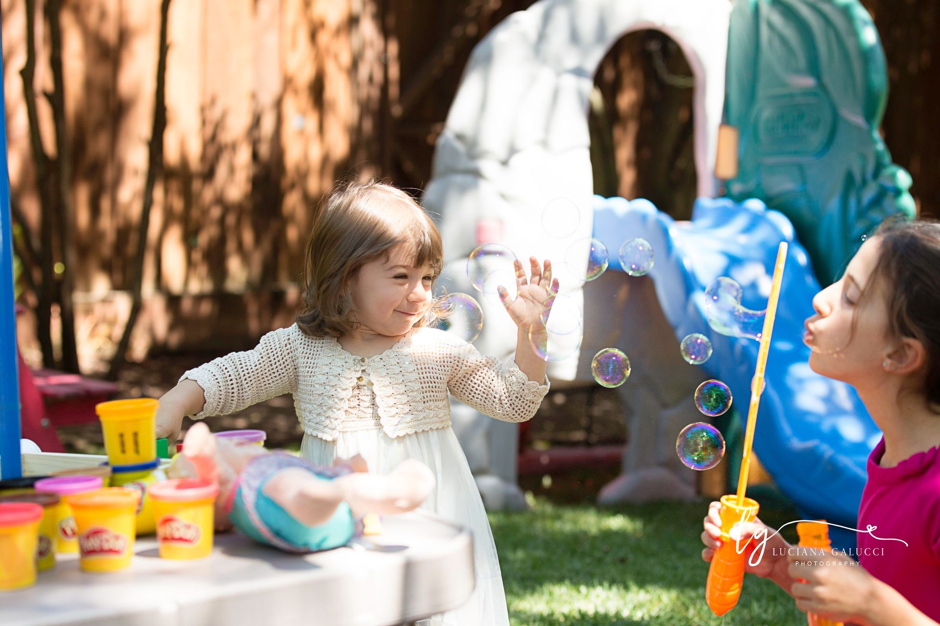 Older sister blowing bubbles to her little sister