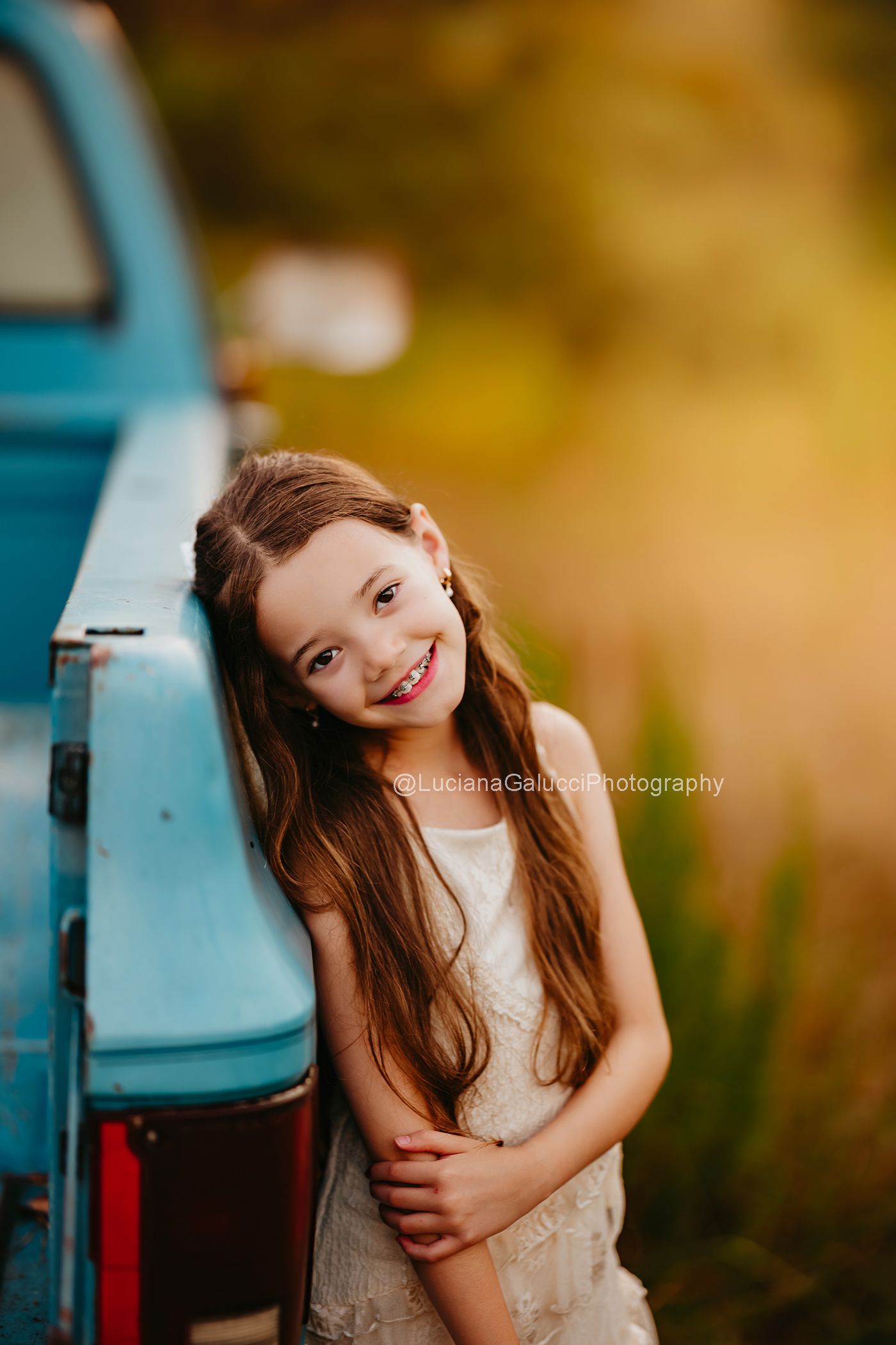 Children standing beside a vintage blue truck at a private farm during a Raleigh fall family session.