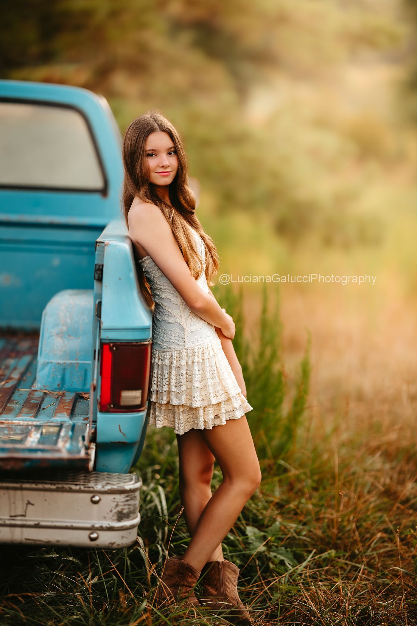 Teen girl standing beside a vintage blue truck at a private farm during a Raleigh Portrait session.