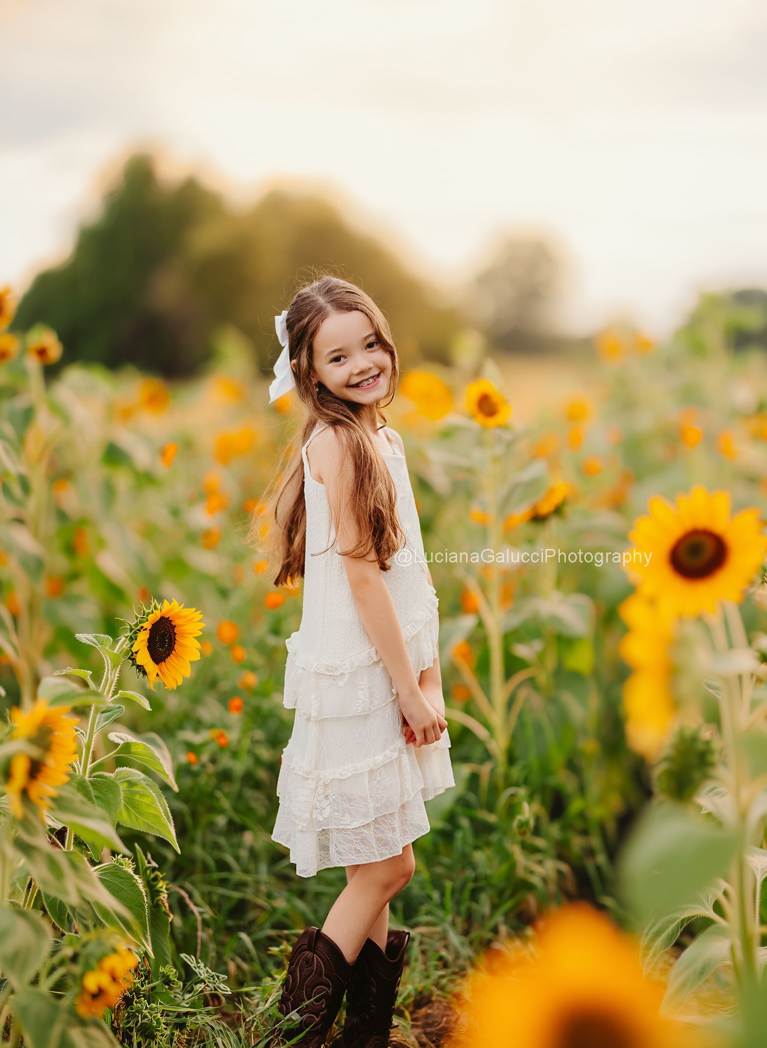Beautiful outdoor child portrait surrounded by sunflowers and wildflowers.