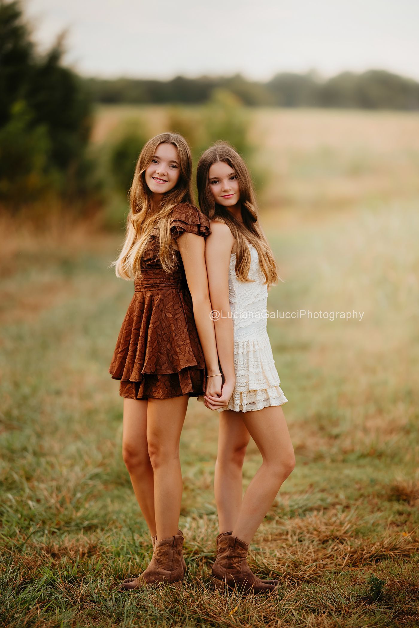 Twin sisters walking through golden grass during an outdoor fall family photography session in Raleigh.
