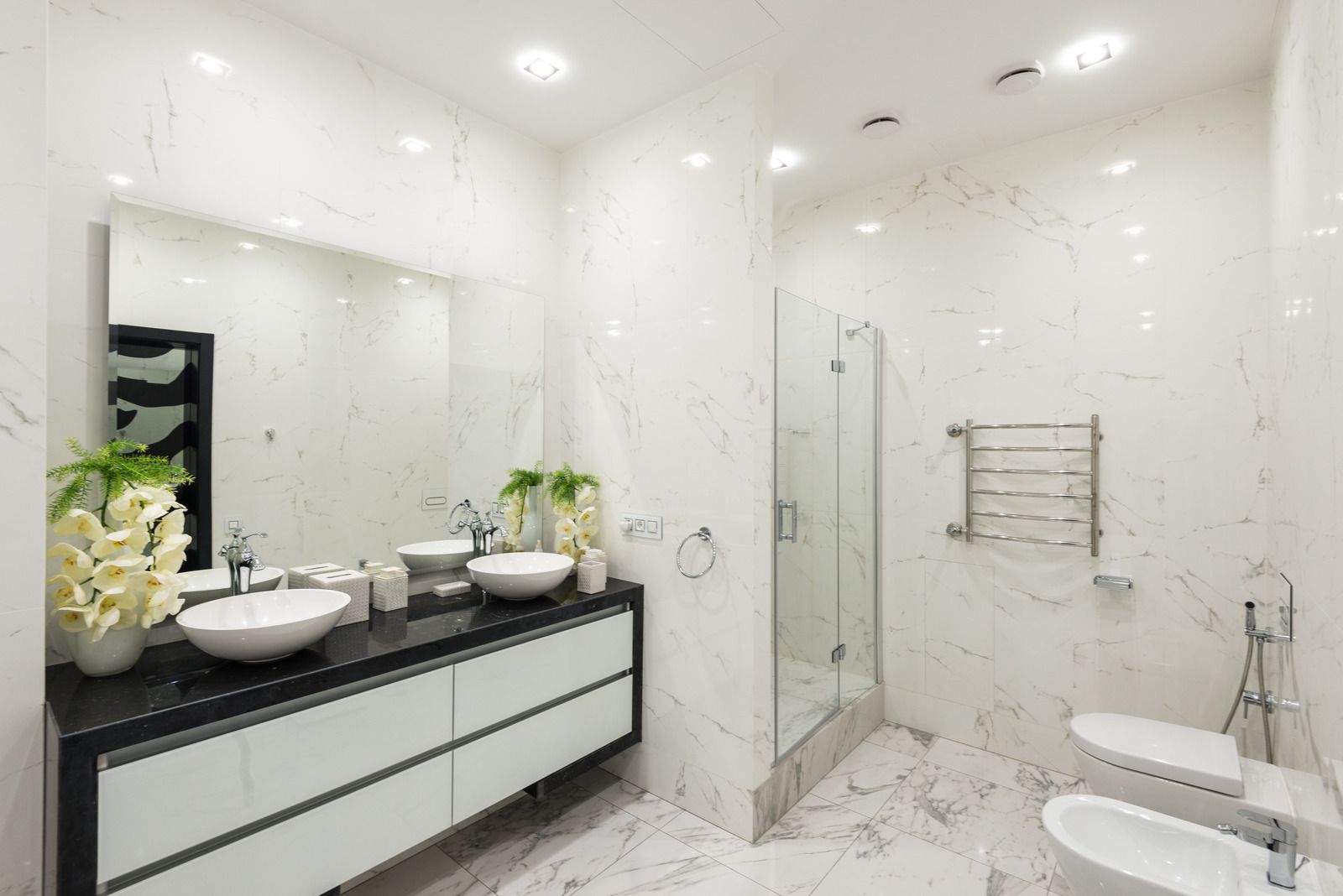A bathroom with two sinks , a toilet and a shower.