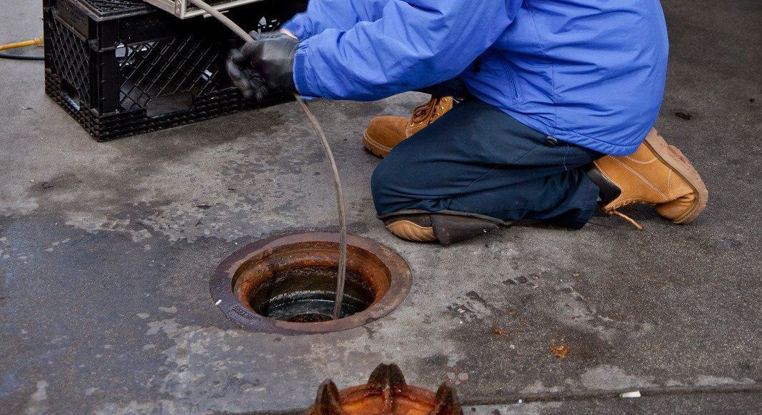 A man is kneeling down in front of a manhole cover.
