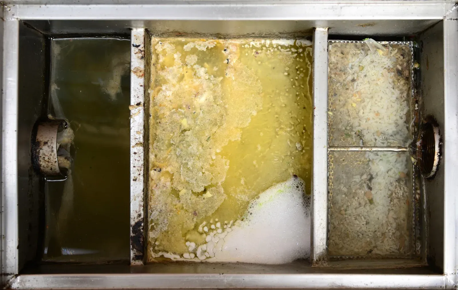 A stainless steel drain with a lot of dirty water in it.