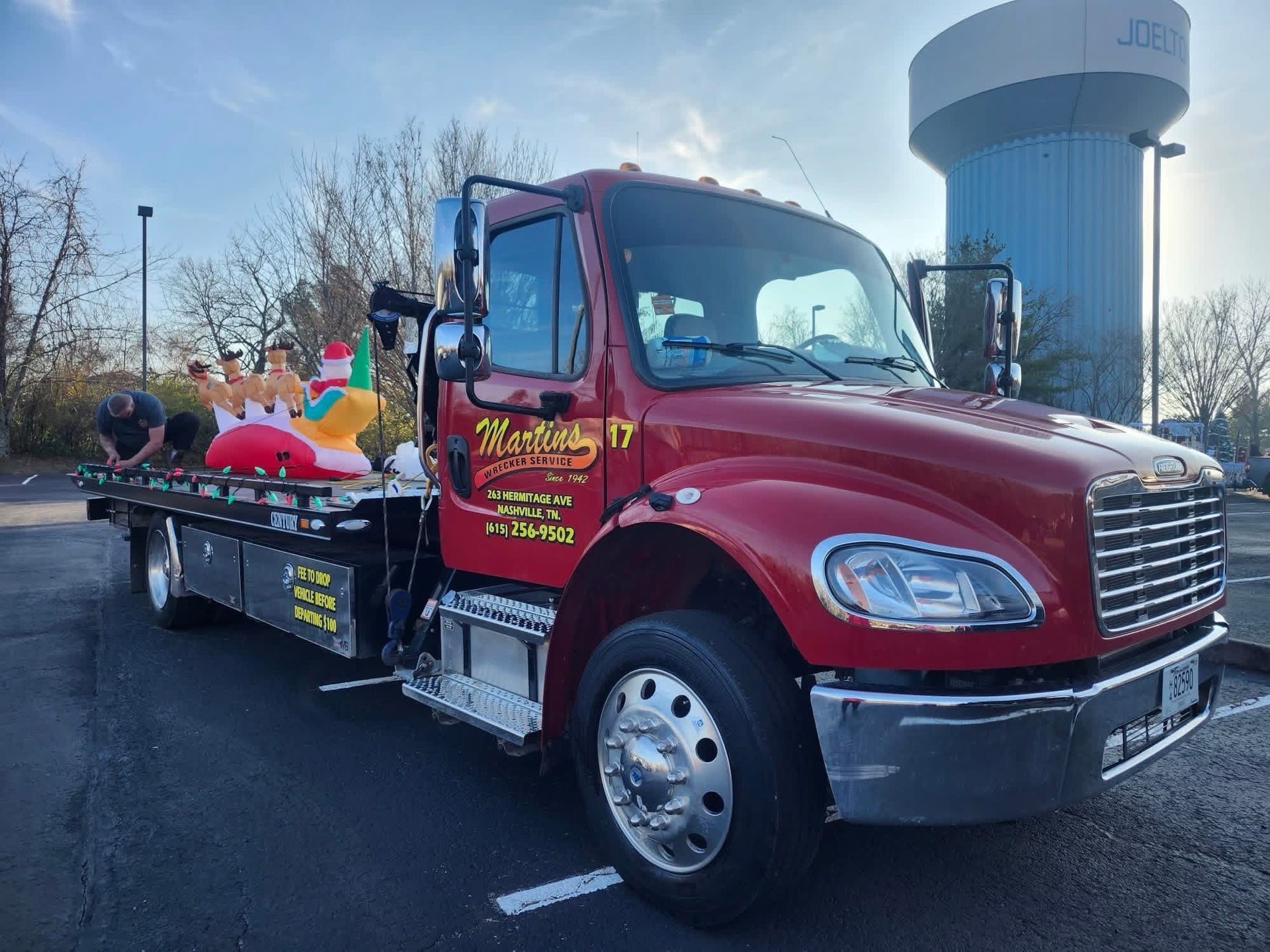 Red tow truck with toys on the bed, parked in front of a water tower. Red tow truck with toys on the bed, parked in front of a water tower.