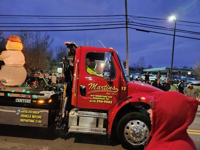 Red tow truck with a snowman on the back, in a nighttime parade. Red tow truck with a snowman on the back, in a nighttime parade.