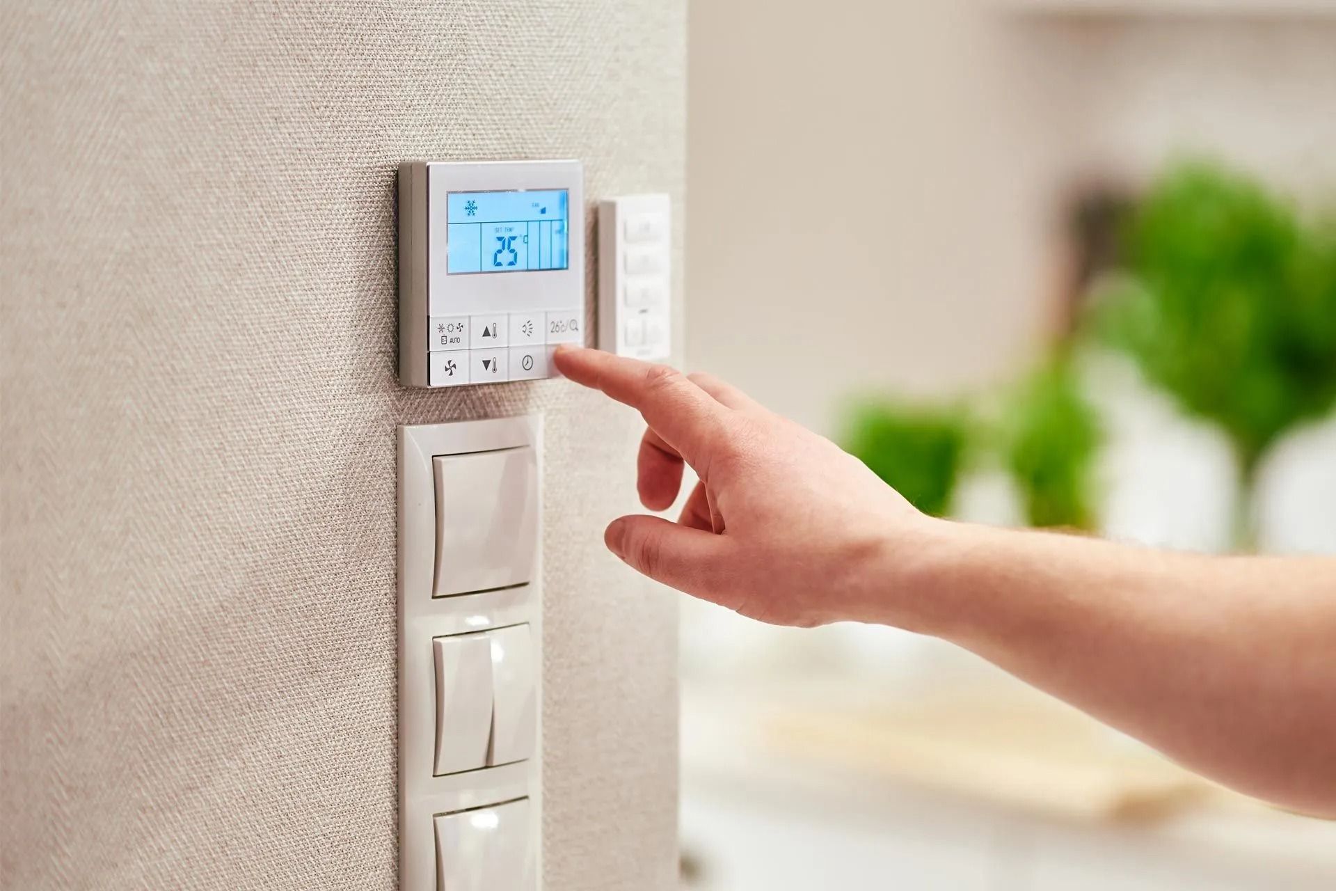 A person is adjusting a thermostat on a wall.