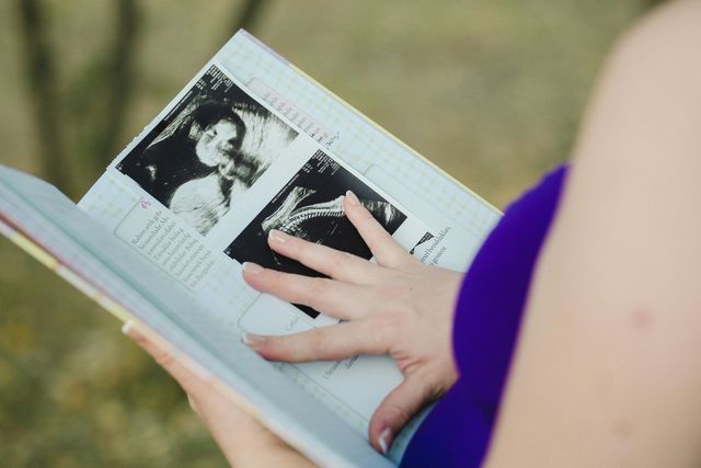 A woman is holding a book with a picture of a baby on it
