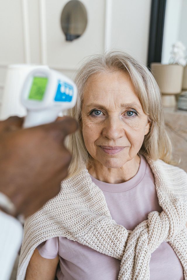 An elderly woman is sitting on a couch getting checked at Dr. Symonetts office