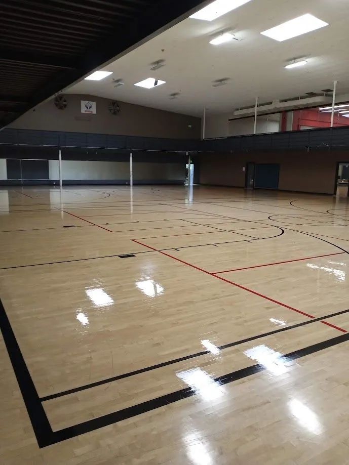 A large empty gym with a wooden floor and a basketball court.